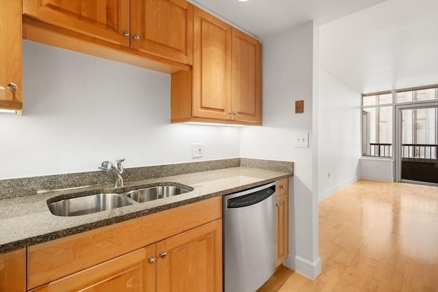 kitchen featuring stainless steel dishwasher, light wood-type flooring, sink, and dark stone counters