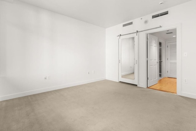 unfurnished bedroom with a barn door and carpet floors