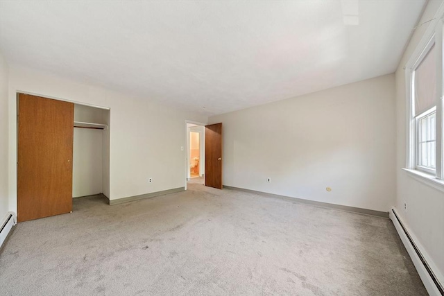 unfurnished bedroom with baseboards, light carpet, baseboard heating, and a closet