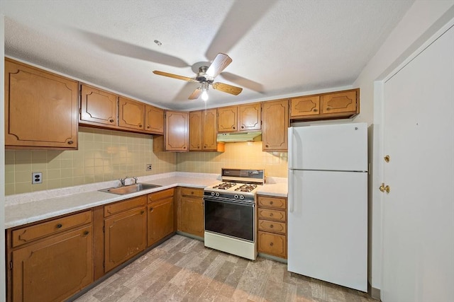 kitchen featuring light wood-style flooring, under cabinet range hood, white appliances, ceiling fan, and a sink