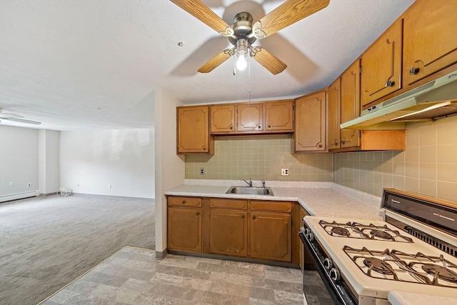 kitchen with a sink, white gas range oven, under cabinet range hood, light countertops, and a ceiling fan