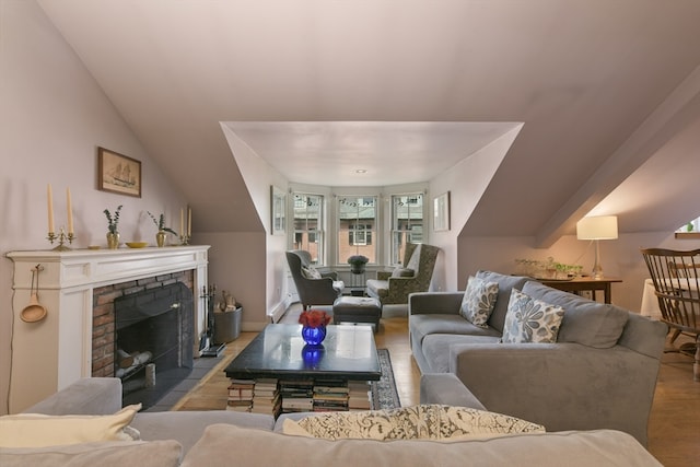 living room with vaulted ceiling, light hardwood / wood-style flooring, and a fireplace