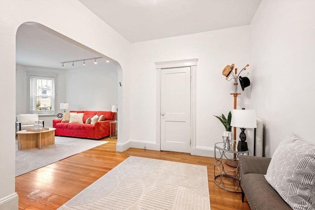 living area with light wood-style floors, baseboards, and arched walkways