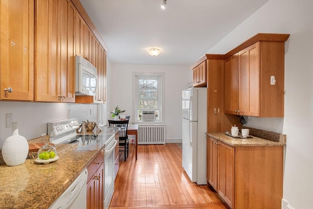 kitchen featuring light stone countertops, radiator heating unit, light wood-style floors, and white appliances
