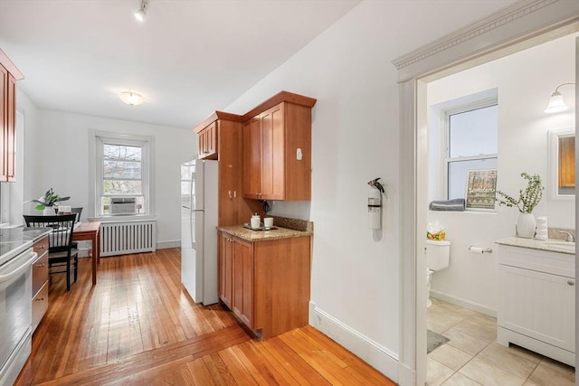 kitchen with radiator, light wood finished floors, electric stove, a sink, and freestanding refrigerator