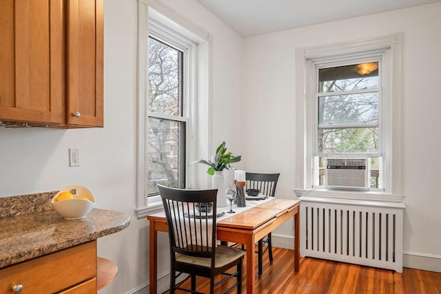 dining area with radiator heating unit, wood finished floors, and baseboards
