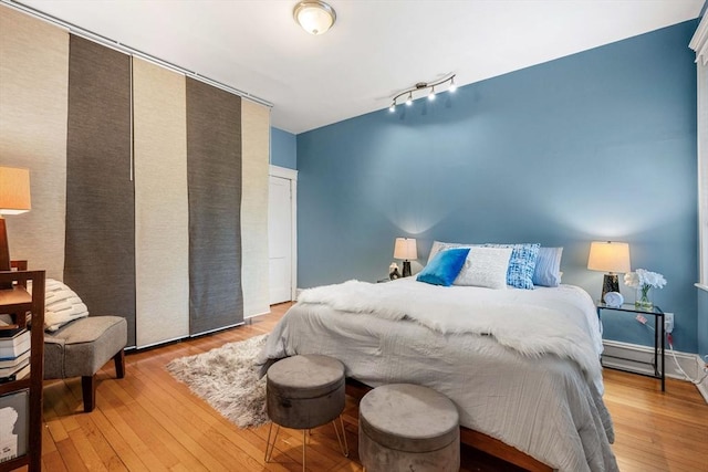 bedroom featuring rail lighting and wood finished floors