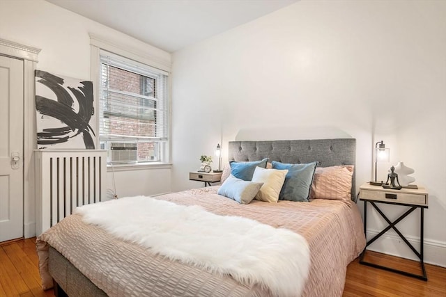 bedroom featuring radiator, wood finished floors, and cooling unit