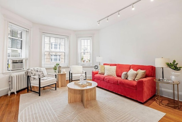 living area featuring radiator, cooling unit, light wood-style flooring, and a wealth of natural light