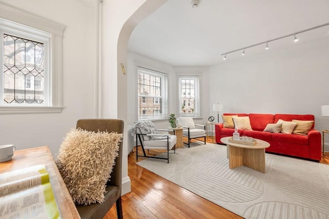 living room featuring track lighting, hardwood / wood-style flooring, and arched walkways