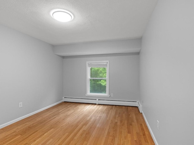48 Decarolis Dr Unit 48, Tewksbury, MA 01876 - empty room with light wood-style flooring, a baseboard heating unit, and a textured ceiling