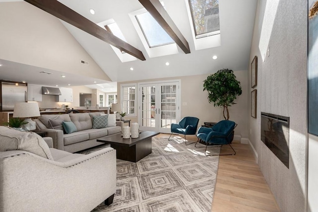 living area featuring high vaulted ceiling, a skylight, a large fireplace, light wood finished floors, and recessed lighting