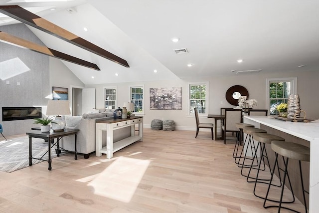 living area featuring light wood finished floors, beam ceiling, plenty of natural light, baseboards, and recessed lighting