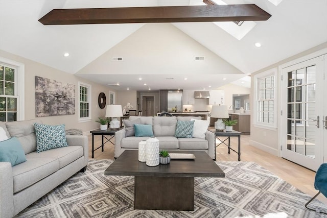 living area with light wood-style flooring, recessed lighting, beamed ceiling, high vaulted ceiling, and a skylight