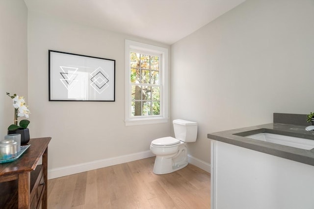 bathroom with wood finished floors, baseboards, toilet, and vanity