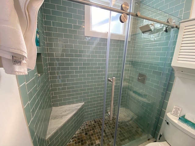 bathroom featuring a shower with shower door and toilet