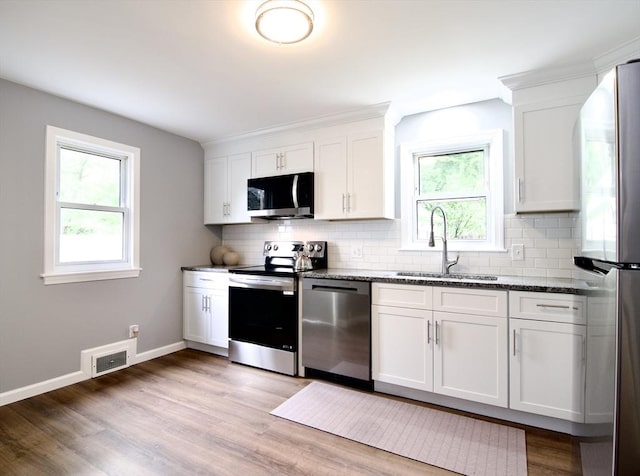 63 Grandview St, Springfield, MA 01118 - kitchen with stainless steel appliances, a sink, backsplash, dark stone counters, and plenty of natural light