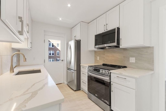 kitchen featuring stainless steel appliances, white cabinetry, sink, and light stone counters