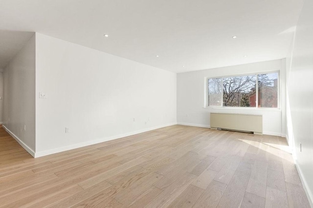 empty room with radiator and light hardwood / wood-style flooring