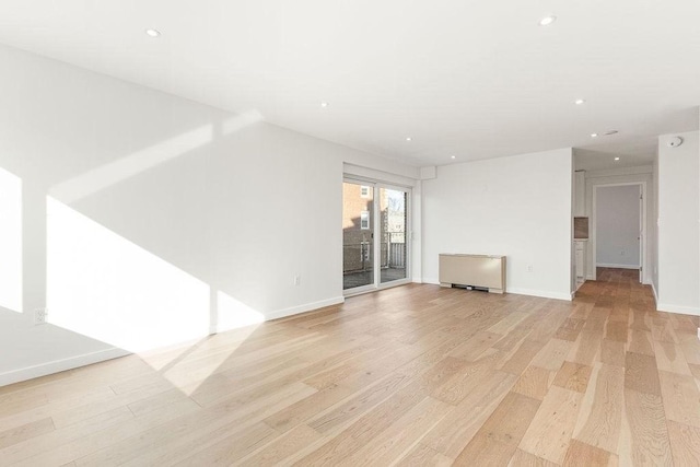 unfurnished living room with radiator and light hardwood / wood-style floors