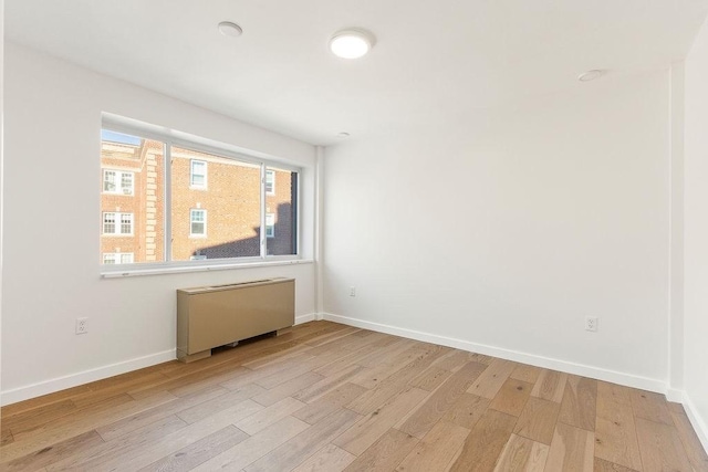 unfurnished room featuring radiator heating unit and light wood-type flooring