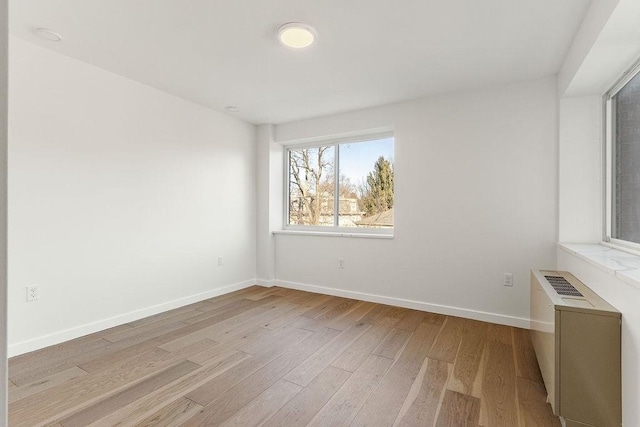 spare room featuring radiator and light hardwood / wood-style floors