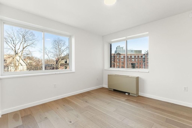 unfurnished room with radiator heating unit and light wood-type flooring