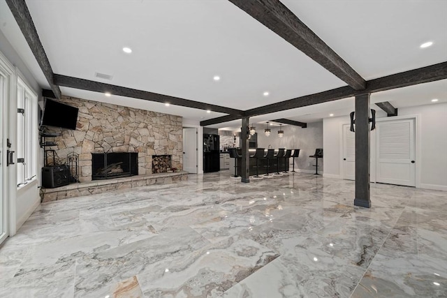 unfurnished living room with beamed ceiling, bar, and a fireplace