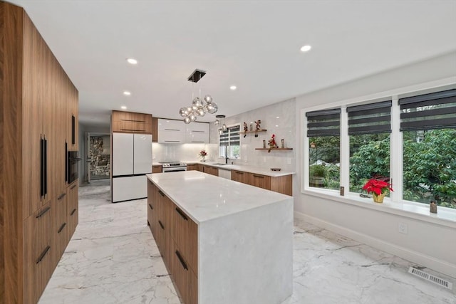 kitchen with decorative backsplash, stainless steel appliances, pendant lighting, an inviting chandelier, and a center island