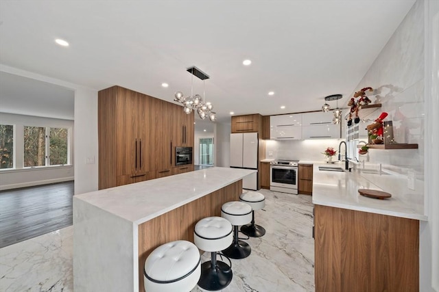 kitchen featuring stainless steel range with electric stovetop, sink, pendant lighting, white refrigerator, and white cabinets