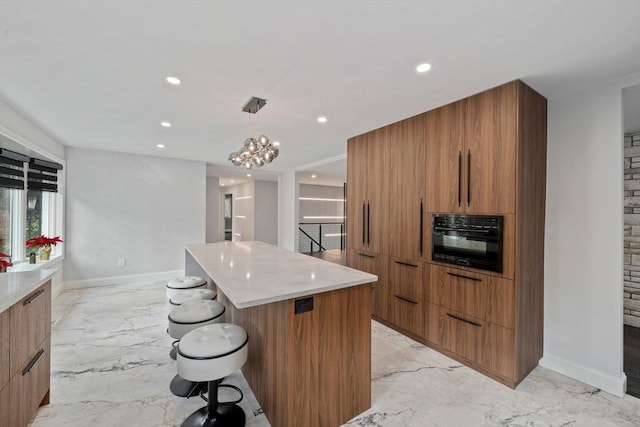 kitchen featuring a breakfast bar, an inviting chandelier, oven, hanging light fixtures, and a kitchen island