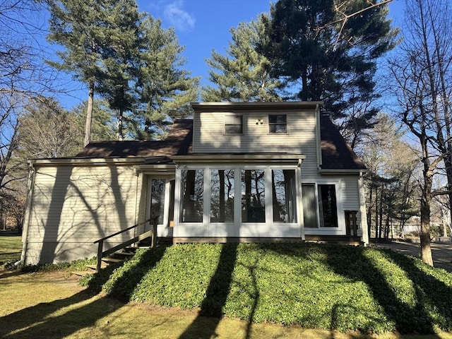 back of property with a lawn and a sunroom