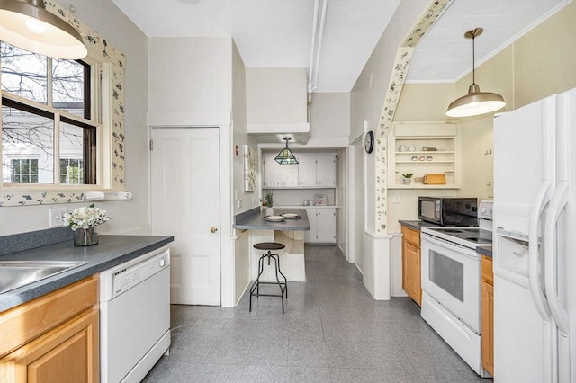 kitchen with dark countertops, a kitchen breakfast bar, hanging light fixtures, white appliances, and a sink