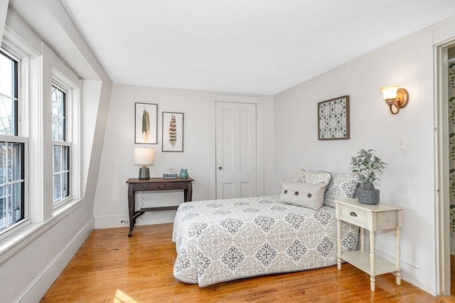 bedroom with a closet, light wood-style flooring, and baseboards