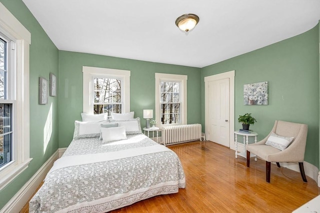 bedroom with radiator, baseboards, and wood finished floors