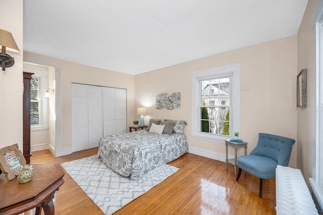 bedroom with wood finished floors, a closet, and baseboards