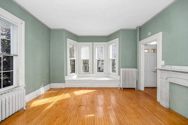 unfurnished living room featuring radiator heating unit, baseboards, and wood-type flooring