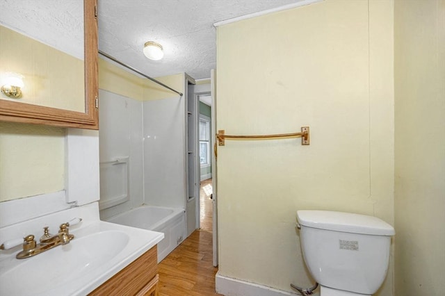 bathroom with vanity, wood finished floors, washtub / shower combination, a textured ceiling, and toilet