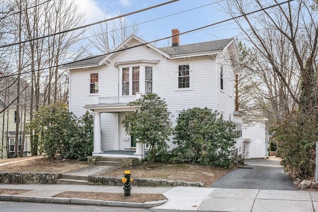 view of front of property with driveway, roof with shingles, and a chimney