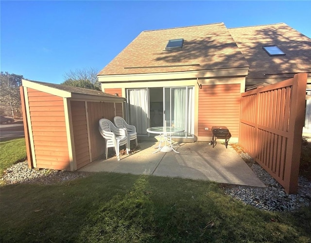 rear view of house featuring an outdoor structure, a patio area, fence, and a lawn