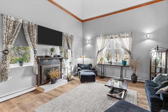 living room featuring a tiled fireplace, a baseboard heating unit, wood finished floors, a high ceiling, and baseboards