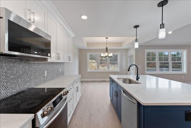 kitchen featuring blue cabinets, a raised ceiling, white cabinets, and appliances with stainless steel finishes