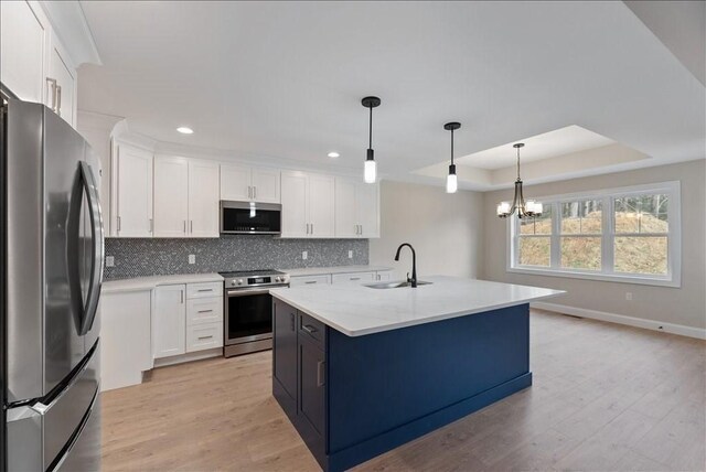 kitchen featuring white cabinetry, sink, stainless steel appliances, and an island with sink