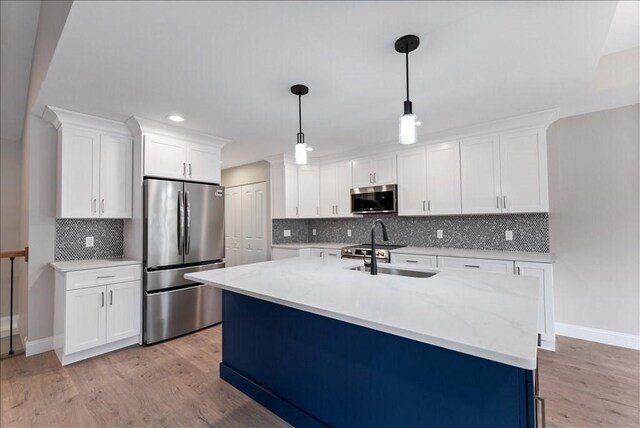 kitchen with pendant lighting, white cabinetry, sink, stainless steel appliances, and light wood-type flooring