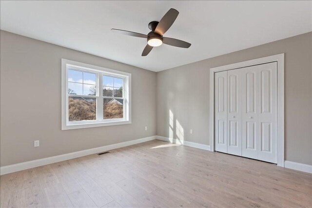 unfurnished bedroom with light hardwood / wood-style flooring, a closet, and ceiling fan