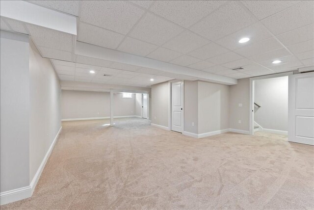 basement featuring light colored carpet and a drop ceiling