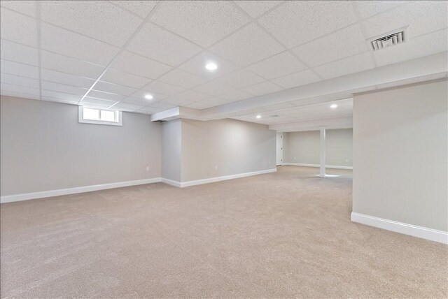 basement featuring a drop ceiling and light colored carpet