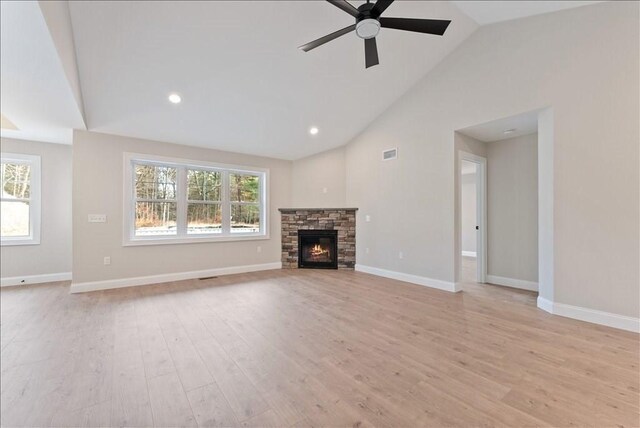 unfurnished living room with ceiling fan, high vaulted ceiling, a fireplace, and light wood-type flooring