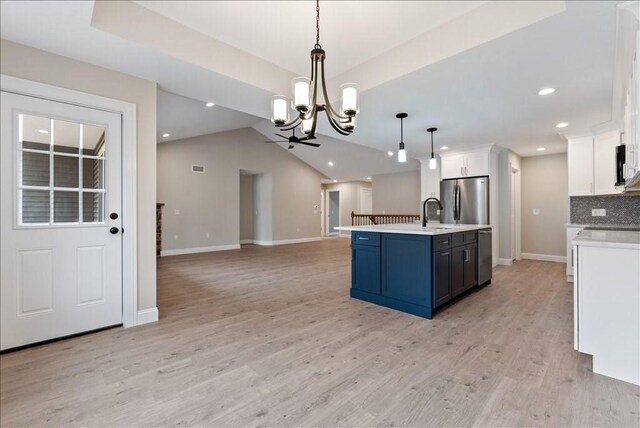 kitchen with pendant lighting, blue cabinets, white cabinetry, a kitchen island with sink, and stainless steel appliances