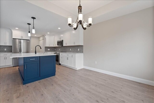 kitchen featuring pendant lighting, tasteful backsplash, sink, white cabinets, and stainless steel appliances